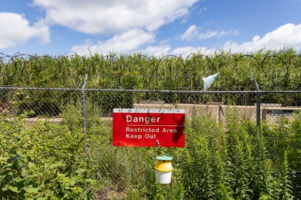 A fence divides Calumet Park and a shoreline dump site at the mouth of the Calumet River on July 18, 2024. (Brian Cassella/Chicago Tribune)