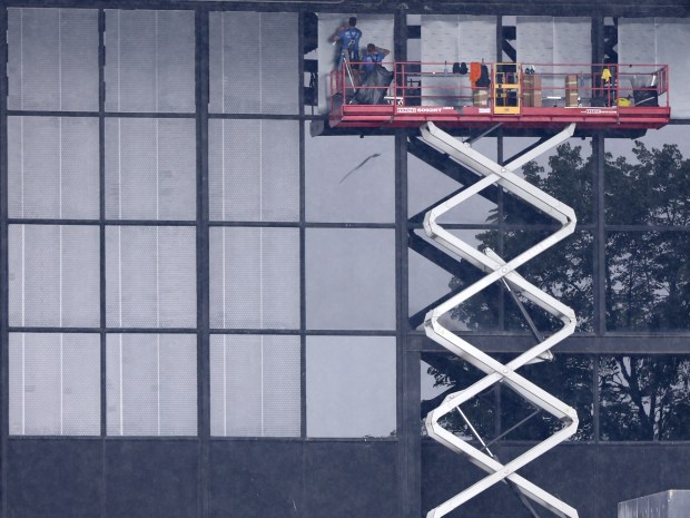 Workers apply window film on July 9, 2024, at McCormick Place Lakeside Center to help reduce bird collisions. (Antonio Perez/Chicago Tribune)