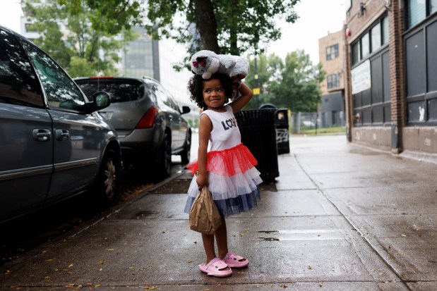 Ashlyng Febres, 4, from Venezuela, carries a stuffed bear as rain falls outside a migrant shelter on North Ogden Avenue on July 29, 2024, in Chicago. Most migrants in Chicago left Venezuela because of economic crisis or political persecution in their home country. (Armando L. Sanchez/Chicago Tribune)