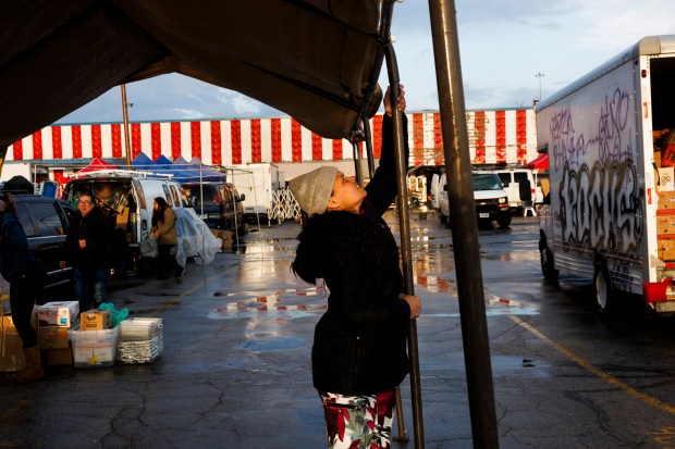 Karina Fuentes works at the Swap-O-Rama flea market after commuting from the Inn of Chicago migrant shelter early in the morning of March 30, 2024. Fuentes earns about $200 a week helping a woman sell handmade crafts and non-perishable food at the flea market in the Back of the Yards neighborhood. (Armando L. Sanchez/Chicago Tribune)