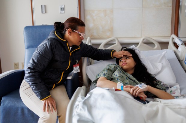 Karina Fuentes sits next to her 15-year-old daughter Janexsys Fuentes at Lurie Children's Hospital on May 23, 2024 in Chicago. Janexsys was hospitalized after she had a seizure at the Inn of Chicago migrant shelter. (Armando L. Sanchez/Chicago Tribune)