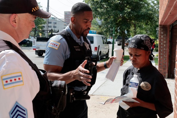 Chicago police Sgt.Chris Schenk, left, and Officer Paris Edwards speak with area resident Mary Young as they canvas the neighborhood adjacent to the United Center on July 26, 2024, to pass out brochures and provide residents with public safety, road closures and transportation information to area residents in preparation for the Democratic National Convention. (Antonio Perez/Chicago Tribune)