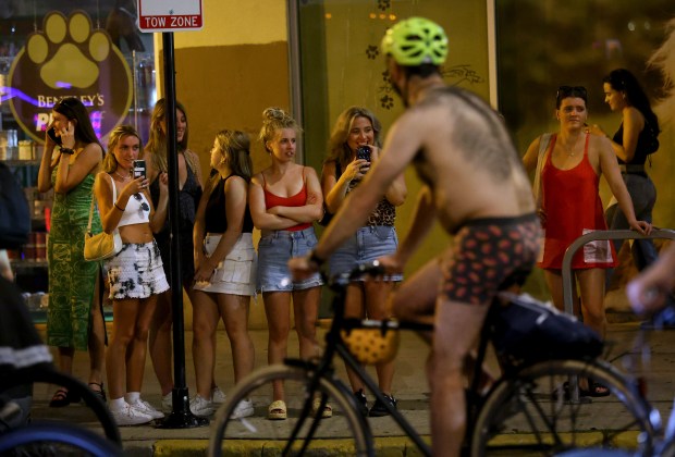 A group of people watch as cyclists ride by on Wells Street while participating in the World Naked Bike Ride through Chicago on June 29, 2024. (Chris Sweda/Chicago Tribune)