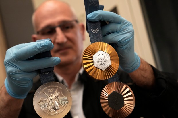 An employee holds medals for the upcoming 2024 Paris Olympic and Paralympic Games after the finishing touches were added, in the workshops of La Monnaie de Paris on June 25, 2024. (AP Photo/Christophe Ena)