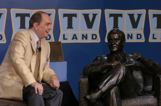 Bob Newhart smiles during a TV interview while seated near a statue in his likeness as Dr. Robert Hartley, the psychologist played by Bob Newhart in the 1970s television show, on July 27, 2004. The statue was unveiled in the Plaza of the Americas on Michigan Ave in Chicago. (David Klobucar/Chicago Tribune)