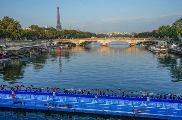 Athletes dive into the Seine River from the Alexander III bridge on the start of the first leg of the women's triathlon test event for the 2024 Paris Olympics on Aug. 17, 2023. (AP Photo/Michel Euler)