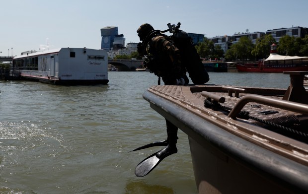 A military diver dives into the Seine river, before inspecting a boat Wednesday, July 17, 2024 in Paris. France's armed forces held a demonstration of the security measures planned on the River Seine, both in and out of the water, to make it safe for athletes and spectators during the opening ceremony of the Paris Olympics. Organizers have planned a parade of about 10,000 athletes through the heart of the French capital on boats on the Seine along a 6-kilometer (3.7-mile) route at sunset on July 26. (AP Photo/Aurelien Morissard)