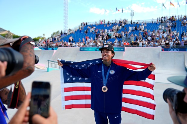 Nyjah Huston, of the United States, poses for photos after winning the bronze medal in the men's skateboard street final at the 2024 Summer Olympics, Monday, July 29, 2024, in Paris, France. (AP Photo/Frank Franklin II)