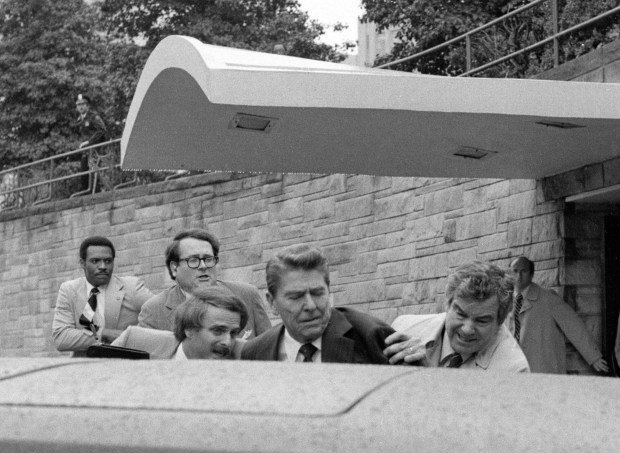 FILE - President Ronald Reagan waves and then looks up before being shoved into the President's limousine by secret service agents after being shot outside a Washington hotel, March 30, 1981. The assassination attempt of former President Donald Trump has parallels to the last time a president or presidential candidate was wounded in 1981 when Ronald Reagan was nearly killed by an assailant's bullet. Reagan's life was spared thanks to the quick actions of a Secret Service agent and the skill of doctors and nurses at a Washington, D.C., hospital. (AP Photo/Ron Edmonds, File)