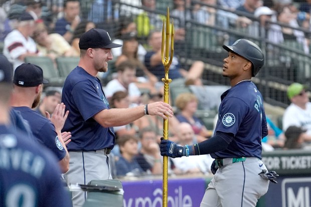 Mariners catcher Luke Raley, left, hands Jorge Polanco the team's home run trident during the fourth inning against the White Sox on July 27, 2024, at Guaranteed Rate Field. (Charles Rex Arbogast/AP)