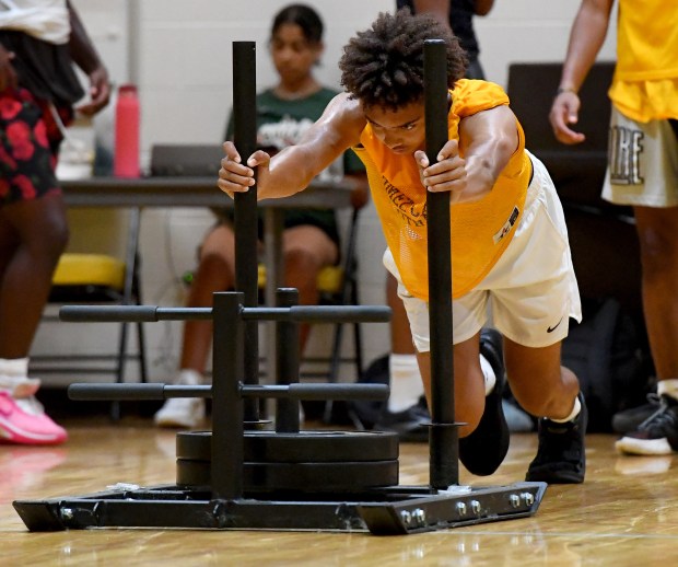 Carmel High School varsity football quarterback Trae Taylor, a sophomore, pushes then drags a 135 pound sled in the gym with his teammates during their voluntary summer camp, Tuesday, July 23, 2024, in Mundelein. (Rob Dicker / News-Sun)