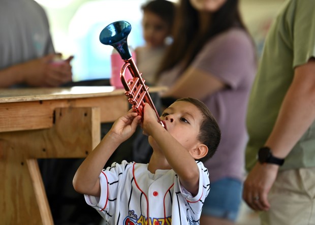 Saul Ortiz, 4, of Wonder Lake, plays with a red and blue trumpet he won as a prize at Vernon Hills Days on July 20, 2024 in Century Park. (Karie Angell Luc/Lake County News-Sun)