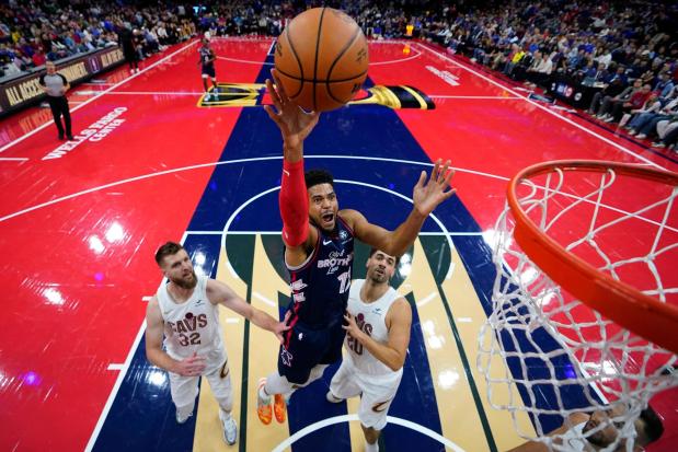 Philadelphia 76ers' Tobias Harris, center, goes up for a shot between Cleveland Cavaliers' Dean Wade, left, and Georges Niang during the first half of an NBA basketball in-season tournament game, Tuesday, Nov. 21, 2023, in Philadelphia. The NBA has agreed to terms on its new media deal, an 11-year agreement worth $76 billion that assures player salaries will continue rising for the foreseeable future and one that will surely change how some viewers access the game for years to come. (AP Photo/Matt Slocum, File)