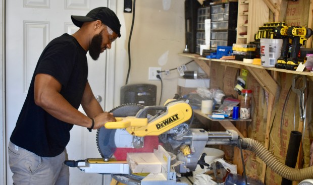 Wearing safety goggles, Ray Brents carefully saws wood that will become part of a table. He owns Ray Brents Design in Naperville, and makes a variety of furniture pieces but specializes in tables. (Steve Metsch/Naperville Sun)