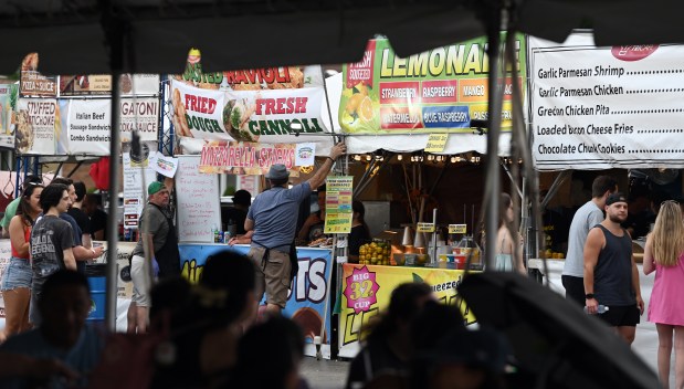 After a cold front came through, vendors reinstall signage that blew down in the wind at the 2024 Island in the City Festival in Norridge on July 13, 2024 in Norridge. (Karie Angell Luc/Pioneer Press)