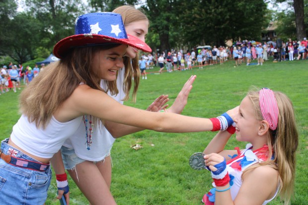 Winnetka residents Kelly Marx, 13, and Sarah Riddle, 13, congratulate Tori Marx, 8, for her win in the girls relay race during the village's Fourth Fest. (Gina Grillo/Pioneer Press)