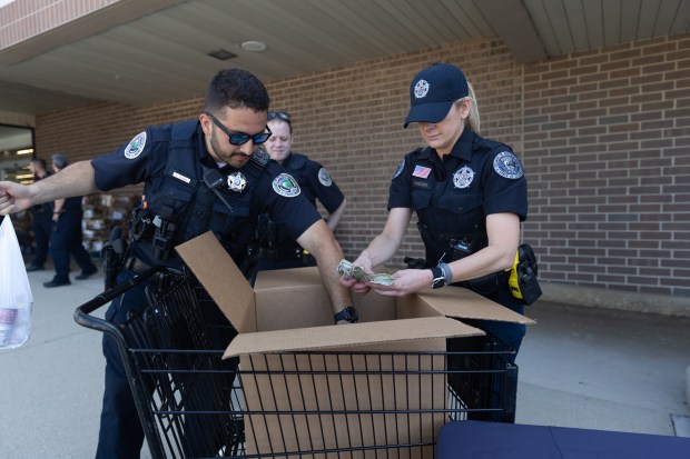 Officer David Olague (left) and Officer Amy Cholewa (right) of the Buffalo Grove Police Department organize collected food donations at Jewel-Osco in Buffalo Grove on Saturday, June 29, 2024. (Trent Sprague/for the Pioneer Press)