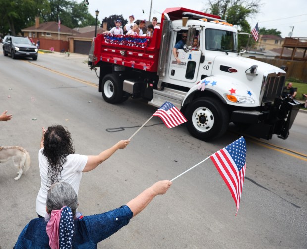 Carmen Robles (left) and Elizabeth Cruz (right) wave American flags during a Fourth of July parade in Elmwood Park on Thursday, July 4, 2024. (Trent Sprague/for the Pioneer Press)