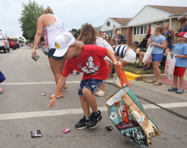 Jaxson Michalski, of Elmwood Park, grabs candy during a Fourth of July parade in Elmwood Park on Thursday, July 4, 2024. (Trent Sprague/for the Pioneer Press)