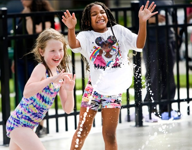 Giulina Ingraffia, 8, left, and Zya Bowser, 8, right, playing in the water during the opening of the new splash pad by city officials at Elmgrove Park Monday, July 1, 2024, in Elmwood Park. (James C. Svehla/for Pioneer Press)