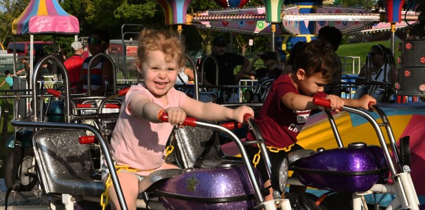 Left, on the motorcycle kiddie ride is Ivy Grace Kittinger, 3, of Elmwood Park at Lincolnwood Fest on July 26, 2024 in Lincolnwood at Proesel Park. (Karie Angell Luc/Pioneer Press)