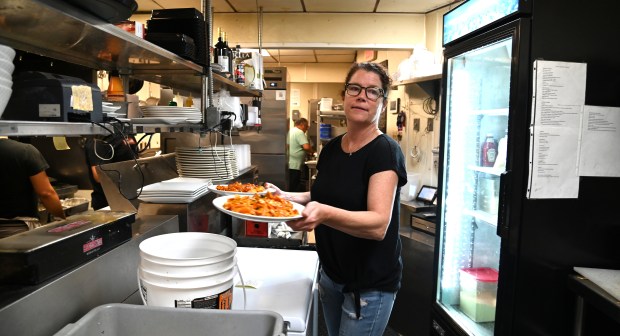 In the kitchen, Katie Keefe of Northbrook, co-owner of Trattoria Oliverii of Northbrook (1358 Shermer Road), brings plates to the dining room at the restaurant on June 25, 2024. (Karie Angell Luc/Pioneer Press)