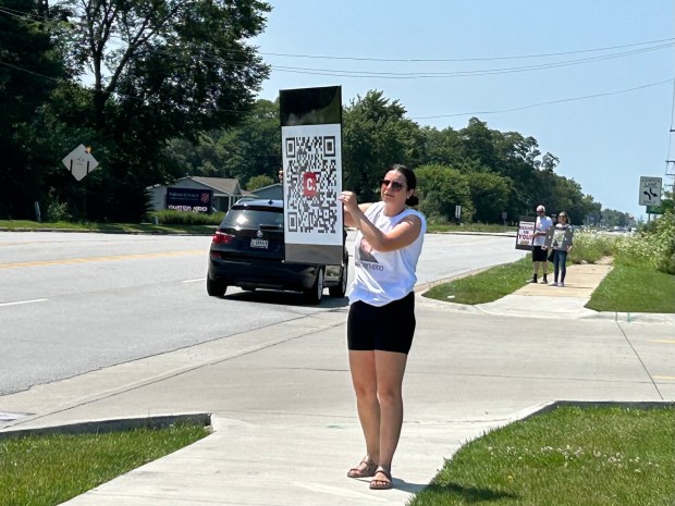 Ana Parrish, Dakota Levi Stevens' aunt, holds a sign with a QR code leading to online petitions seeking justice for Dakota, 10, who died in foster care. She and other family members and supporters protest once a month at Indiana 149 and US 6 and were there on Saturday, July 27, 2024. (Amy Lavalley/Post-Tribune)