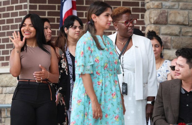 Julie Hurt from Venezuela (left) waves to family members during the naturalization of 50 people from 30 countries by federal Magistrate Judge Abizer Zanzi at the Pavilion at Wolf Lake in Hammond on Wednesday, July 3, 2024. (John Smierciak/for the Post Tribune.