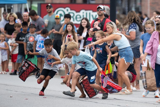 Children run into the street to gather candy thrown from Portage emergency vehicles during the city's 4th of July Parade on Thursday, July 4, 2024. (Kyle Telechan/for the Post-Tribune)
