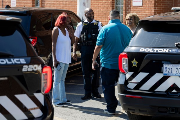 Dolton police Sgt. Terry Young Jr., in white, speaks to people outside the Dolton Police Department July 2, 2024, as people were calling for the release of activist Jedidiah Brown from police custody after he confronted Trustee Andrew Holmes at Monday's Village Board meeting. (Vincent Alban/Chicago Tribune)