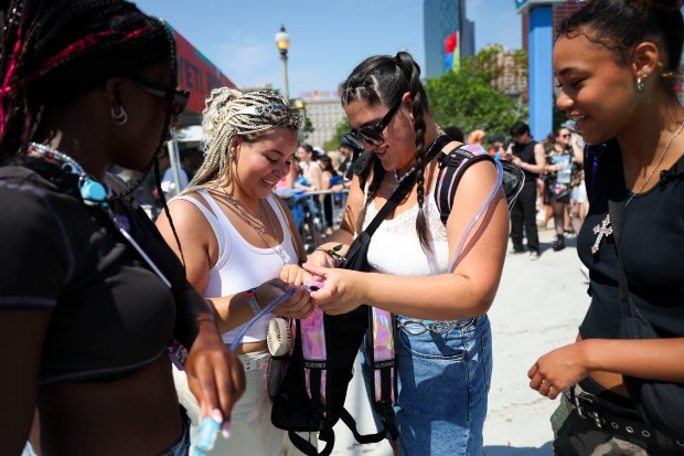 Korah Bass, from left, Bekah Lott, Mackenzie Newton, and Krystal Verdooren, all of Washington, D.C., fix their hydration packs in their backpacks after entering the main entrance on Ida B. Wells Drive at Lollapalooza in Chicago's Grant Park on Aug. 3, 2023.