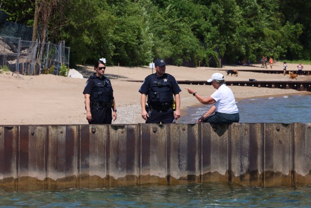 Mary Garrison, a former Winnetka Park District commissioner, right, sits on a seawall and chats with Winnetka Police officers while watching construction on Justin Ishbia lakefront property in Winnetka on Wednesday, July 19, 2023. Since construction started earlier this summer, nearly all of the trees have been clearcut and the bluff has been taken down. The property was once three separate homes. It is now 3.7 acres. (Stacey Wescott/Chicago Tribune)