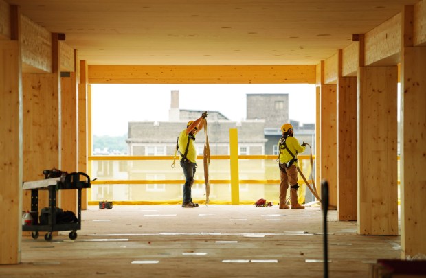 Construction workers Cruz Pantoja, left, and Daniel Buendiia, right, work on the 10th floor of the Ascent apartment building on Aug. 2, 2021 in Milwaukee, Wisconsin. (Stacey Wescott/Chicago Tribune)