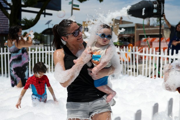 Tiana Schiavone holds her son Giovanni in the bubble playground during the Bubble Works event put on by the Wonder Work Children's Museum in Oak Park on July 14, 2024. (Eileen T. Meslar/Chicago Tribune)