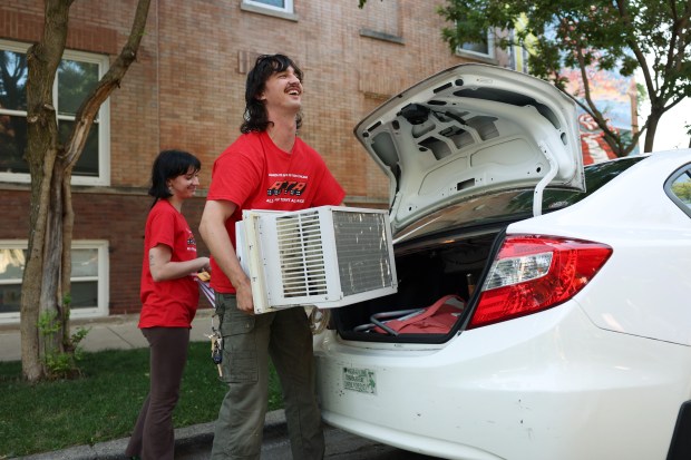 Desmond Quinn unloads an air conditioner to deliver to a resident in the Humboldt Park neighborhood on July 11, 2024, in Chicago. Quinn and Sam Diamonte, left, of the All-Chicago Tenant Alliance program called People's Cooling Army, lend, deliver and install window air conditioners for tenants without adequate cooling in their apartments. (John J. Kim/Chicago Tribune)