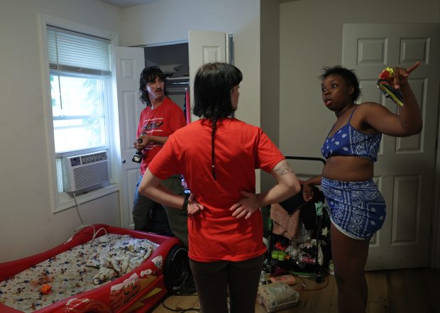 Juanita Taylor, right, talks with Sam Diamonte, center, and Desmond Quinn as Quinn installs an air conditioner at Taylor's residence in Chicago's Humboldt Park neighborhood on July 11, 2024. (John J. Kim/Chicago Tribune)