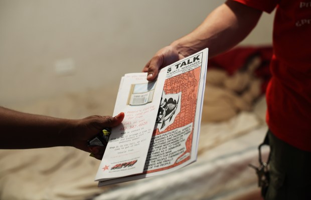 Desmond Quinn, right, hands Juanita Taylor information about an air conditioning program and a tenant's rights newspaper after installing an air conditioner at Taylor's residence on July 11, 2024, in Chicago. (John J. Kim/Chicago Tribune)