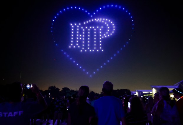 People watch drones light the sky above Wolters Field in Highland Park on July 4, 2023, during a one-year remembrance concert and drone show of the Highland Park shooting. (Trent Sprague/Chicago Tribune)