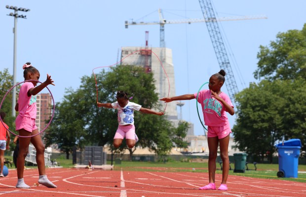 Chicago Park District day campers Emiyah Johnson, left, and her twin sister Eyriana Johnson, right, twirl the jump roper for Azyah Garrett, center, near the Obama Presidential Center (OPC) on July 12, 2024, in Chicago. (Stacey Wescott/Chicago Tribune)