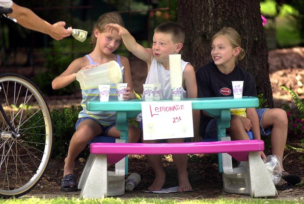 Twins Amy, left, and Laura Drabant, 8, sell lemonade in Wheaton in 2001. The sisters made the lemonade while their neighbor, Charlie DeWitt, 7, joined in the enterprise by providing the cups. (Stephanie Sinclair/Chicago Tribune)