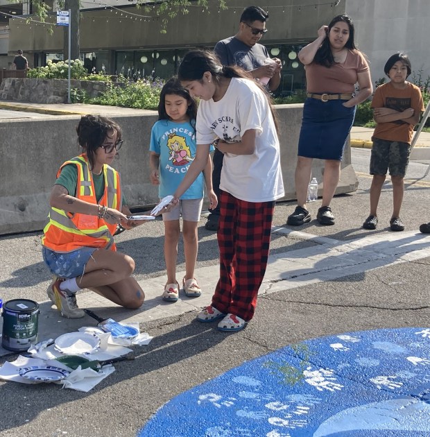 Niya Simone applies paint to the hands of participants so they can place their handprint on a crosswalk mural. (Steve Sadin/For the Lake County News-Sun)