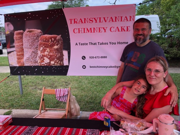 Dan and Renata Savin, shown with their daughter Catherine, sell Transylvanian Chimney Cakes in three flavors, as well as other baked goods, at their booth at the Park Ridge Farmers Market on June 29, 2024.