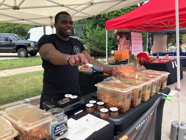 Leleng "Eric" Kpandang offers a taste of flavored nuts to a potential customer at the Park Ridge Farmers Market on June 29, 2024.