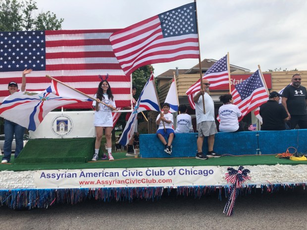 At Skokie's 2024 July Fourth parade, riders on the Assyrian American Civic Club of Chicago wave to the crowd.