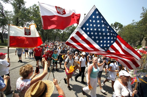 Thousands of walkers approach the end of their journey on Sunday as the walk under the Polish and American flags during the Polish Pilgrimage from Chicago to the Our Lady of Czestochowa Shrine in Merrillville, In. on August 8, 2021. (John Smierciak for the Post Tribune)