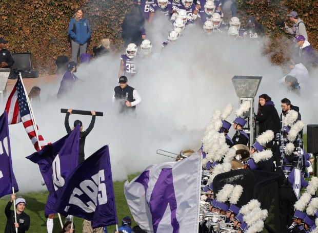 Northwestern coach David Braun, center left, takes the field through pyrotechnic smoke before a game against Iowa on Nov. 4, 2023, at Wrigley Field. (John J. Kim/Chicago Tribune)