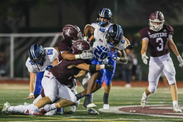 Lincoln Way East's Zion Gist (20) fights for extra yards against Lockport during a SouthWest Suburban Blue game in Lockport on Friday, Sept. 29, 2023.