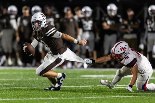 Mount Carmel's Jack Elliott (9) escapes a potential sack against St. Rita during a CCL/ESCC game in Chicago on Friday, Sept. 15, 2023.