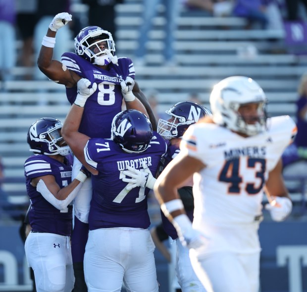 Northwestern wide receiver A.J. Henning (8) is held up by his teammates after scoring a touchdown in the fourth quarter of a game against UTEP at Ryan Field on Sept. 9, 2023.