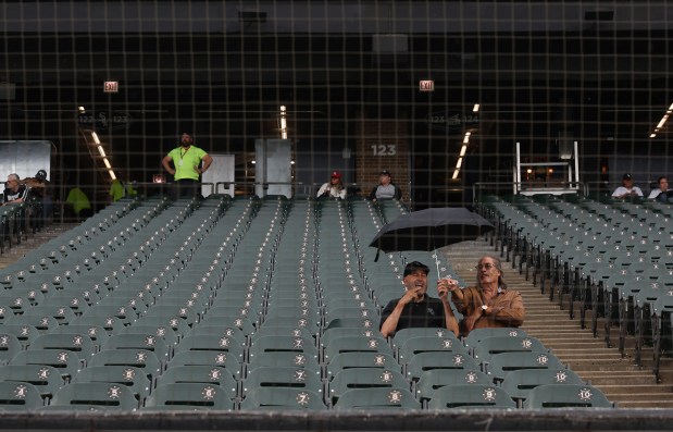 Two fans sit under an umbrella while waiting for a game between the White Sox and Rockies at Guaranteed Rate Field on June 28, 2024. (John J. Kim/Chicago Tribune)